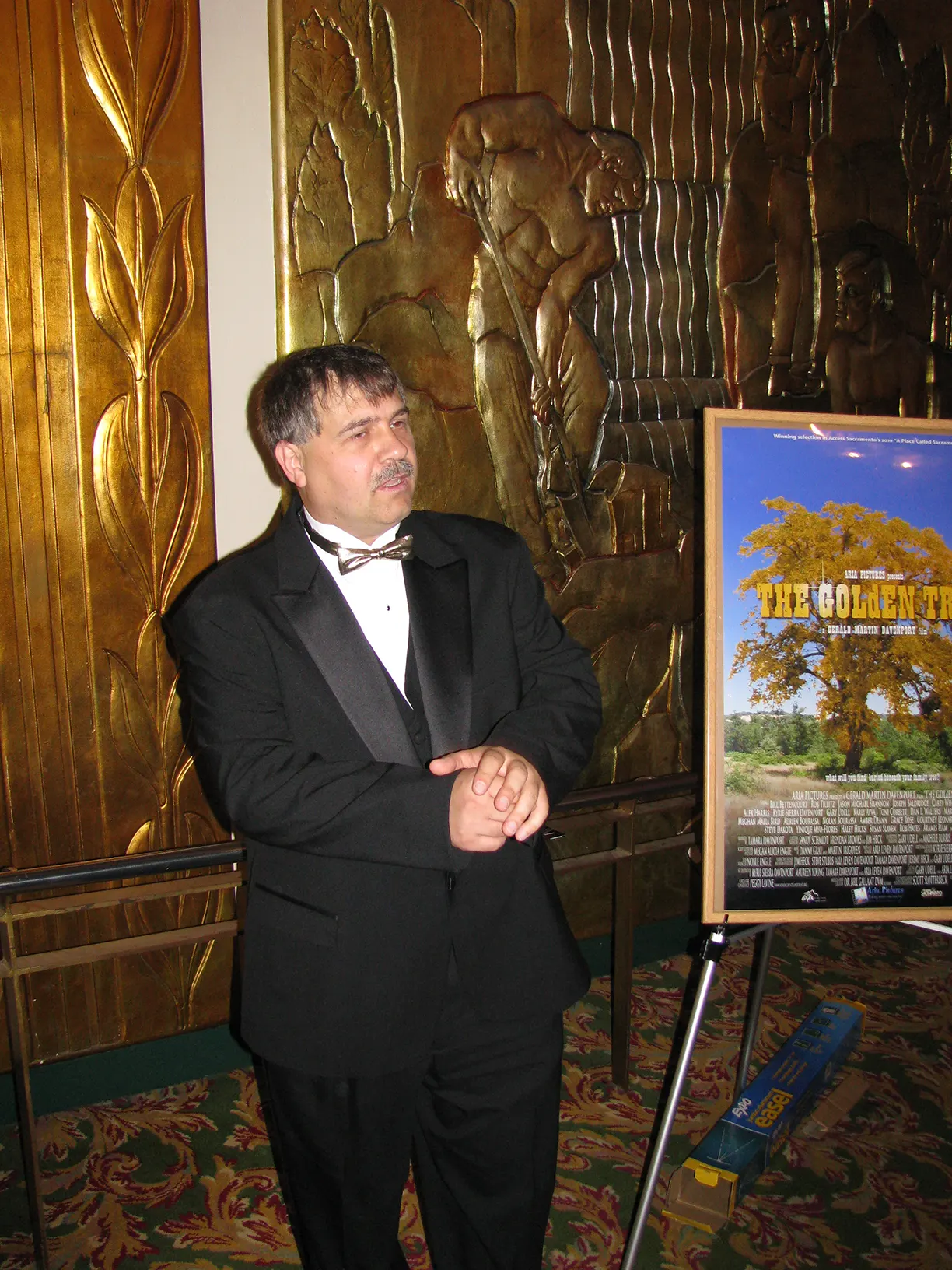 The director standing next to the poster for THE GOLdEN TREE - Access Sacramento- A Place Called Sacramento Film Screening at the Crest Theater in Sacramento, California.